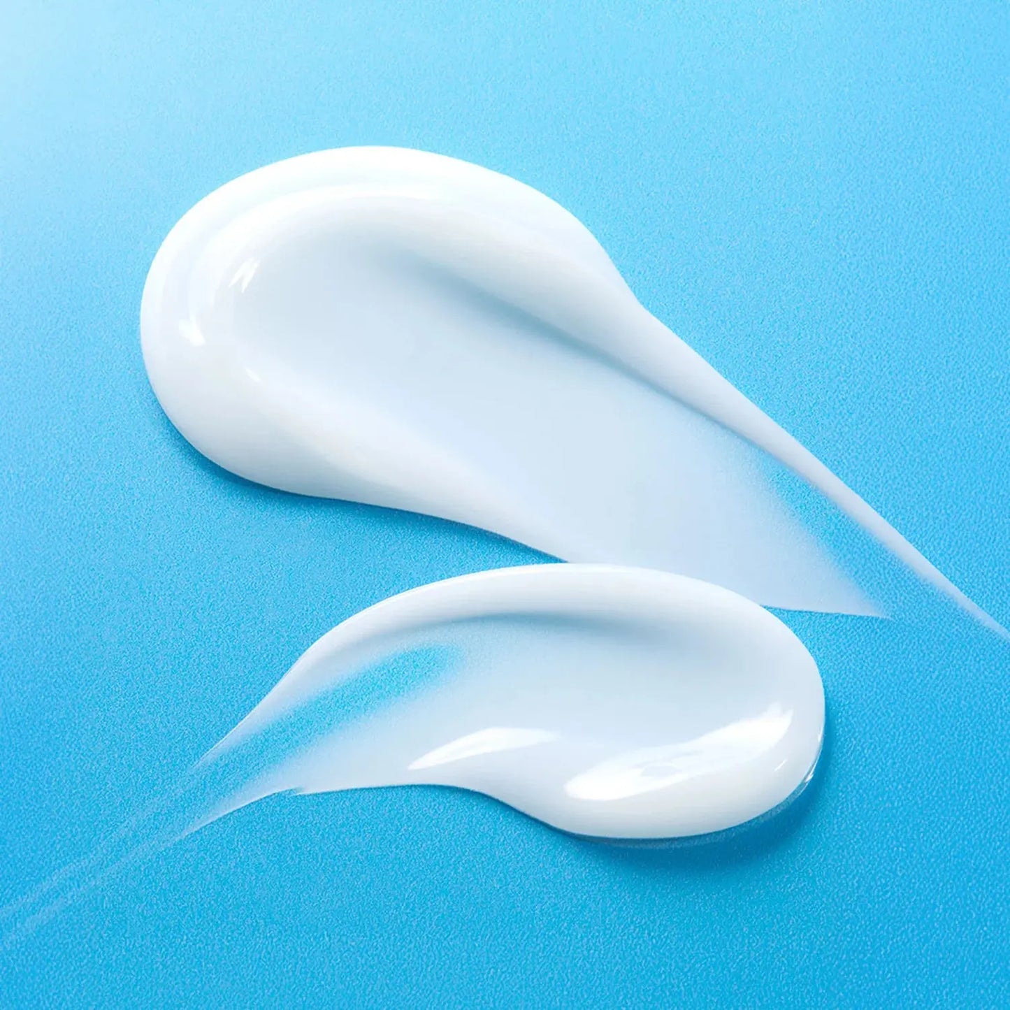 Two smears of white cream on a blue background
