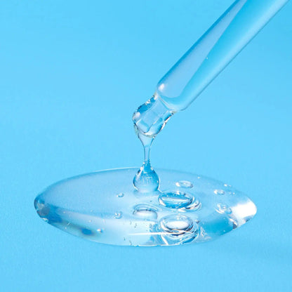 Glass dropper with clear liquid on a blue background
